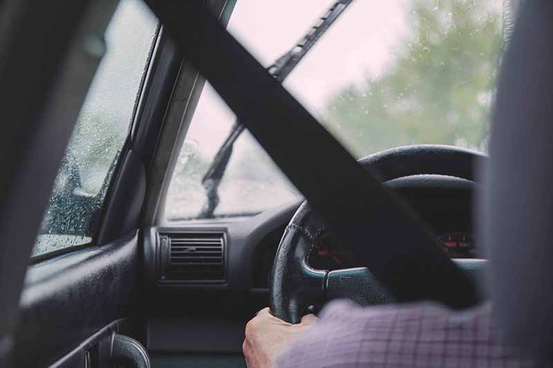 person in car using steering wheel